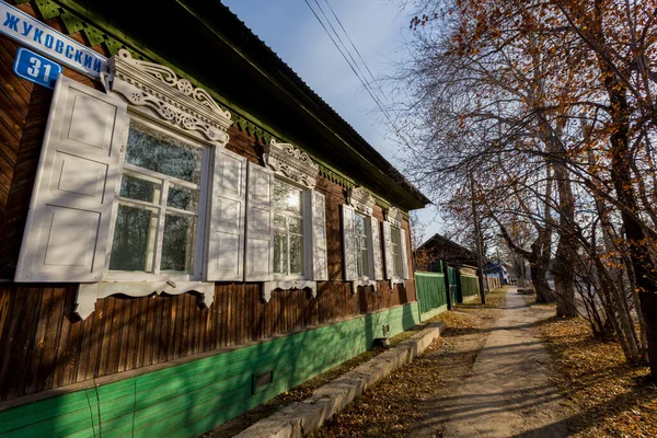 Una vecchia casa di legno di un piano con persiane intagliate in stile russo. Casa in legno sulla strada di una città russa — Foto Stock
