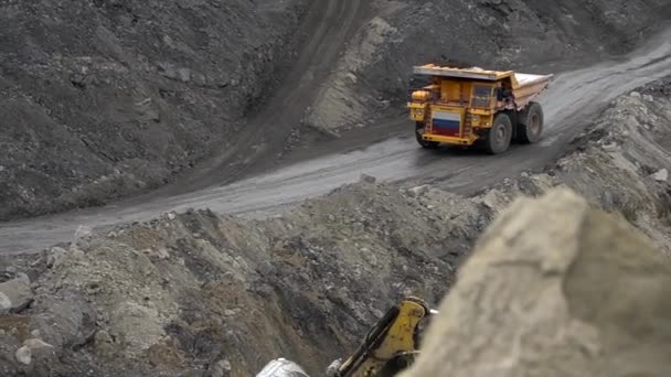 Summer, 2020 - Primorsky Territory, Russia - Above. A yellow Belaz is driving through a quarry with a body loaded with soil against the background of high piles of earth — Stock Footage Summer, 2020 - Primorsky Territory, Russia - Above. A yellow Belaz is driving through a quarry with a body loaded with soil against the background of high piles of earth Stock Footage