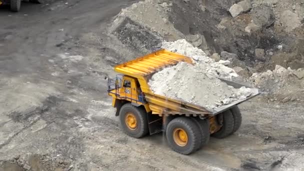 Sommer 2020 - Primorsky Territory, Russland - Oben. Ein gelber Belaz fährt durch einen Steinbruch mit einer mit Erde beladenen Leiche vor dem Hintergrund hoher Erdhaufen — Stockvideo