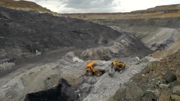 Лето 2020 года - Россия - карьер по добыче угля. Экскаватор загружает грунт в самосвал в угольной шахте — стоковое видео