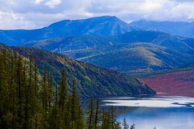 Rus tundrasındaki yüksek dağların arka planında pürüzsüz mavi suyu olan güzel bir göl.