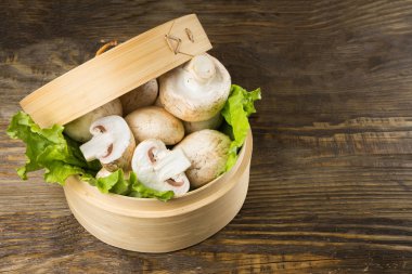 Yuvarlak konteyner ile marul yaprakları ve mantar bir tablo.