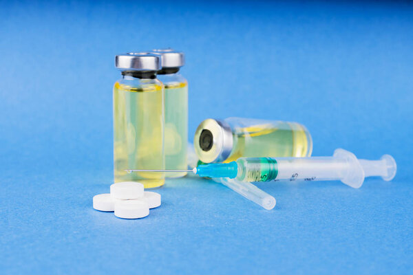 Группа флаконов с лекарствами, таблетками и шприцами на синем столе. Горизонтальная композиция
.