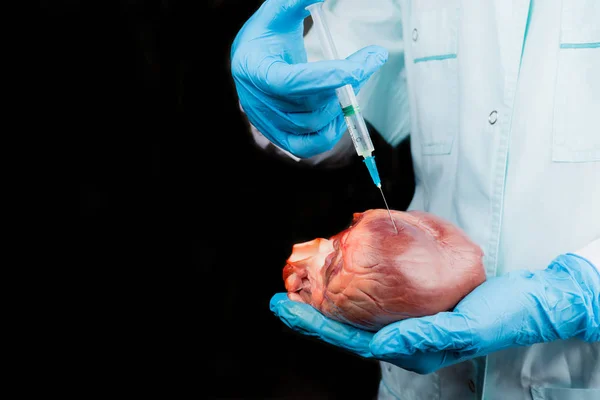 The medical worker makes an injection of the drug into the heart. Dark background. Horizontal composition.