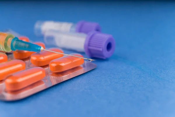 Tablets in a blister, a syringe with the typed medical preparation and test tubes for analyses.. Dope. Drugs. Pharmaceutical preparation. Blue background. Macrophotography. Copy paste