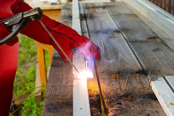 Welder welds two pieces. Hands protected red leather gloves. Copy cpase.