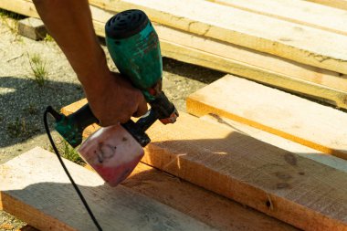 Ahşap ahşap üzerinde boya püskürtme sanayi işçisi. Boya tabancası ile inşaat işçisi. Kopyala Yapıştır.