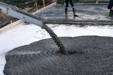 İşçiler Mobil Beton karıştırıcı kullanarak bir konut bina inşaatı için temel dökme. Kopyala Yapıştır