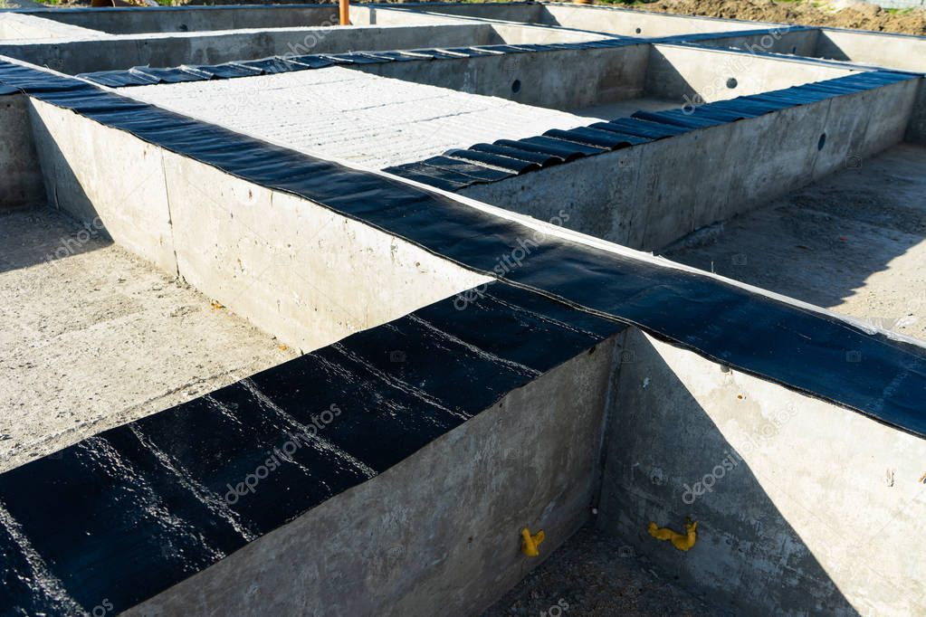 Workers carry out waterproofing of the Foundation for the construction of a wooden house. Copy paste.