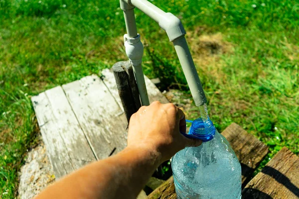 Una persona recoge agua en un recipiente. Problema de suministro de agua . — Foto de Stock