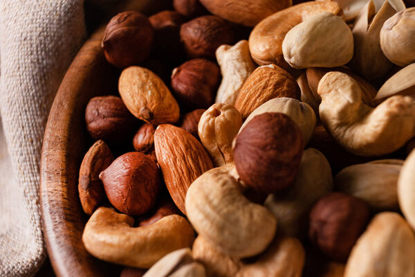Assortment of nuts in wooden bowl on dark wooden table.