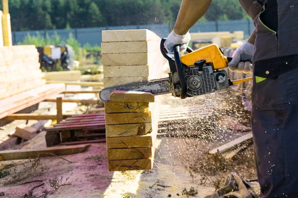 Un operaio sega via una tavola di legno della motosega. Costruzione casa . — Foto Stock