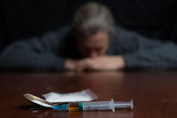 Drogově závislý na stole, který je injekční stříkačka s drogami. Koncepce proti drogám. — Stock fotografie