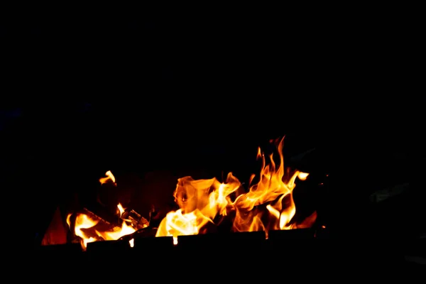 Las llamas de fuego de las brasas ardientes en la parrilla tarde en la noche . — Foto de Stock