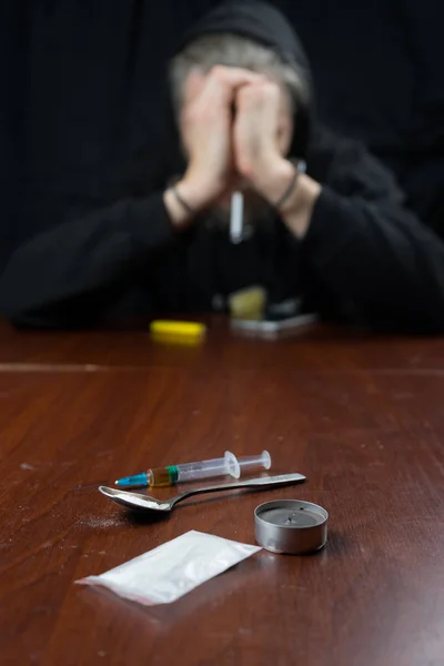 Drogově závislý na stole, který je injekční stříkačka s drogami. Koncepce proti drogám. — Stock fotografie