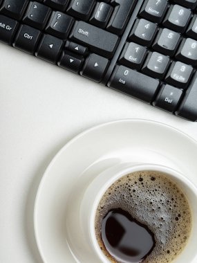 Düz yatıyordu, üst görünüm ofis masa masası. Beyaz arka planda çalışma alanı klavyesi ve kahve fincanı.