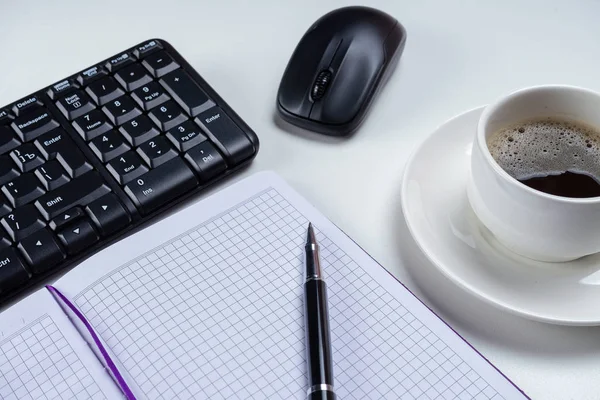 Escritorio de mesa de oficina. Espacio de trabajo con libreta en blanco, teclado, útiles de oficina y taza de café sobre fondo blanco . — Foto de Stock
