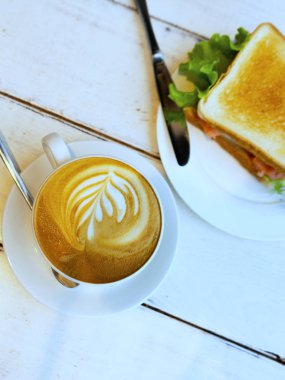 Kahvaltıda jambon, peynir, çeri domates, salatalık ve marul ve espresso kahve ile ekmek sandviç. Seçici odaklama.