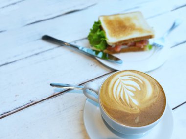 Kahvaltıda jambon, peynir, çeri domates, salatalık ve marul ve espresso kahve ile ekmek sandviç. Seçici odaklama.