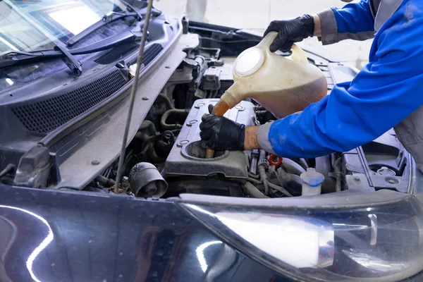 Mecânico de automóveis substituindo e derramando óleo fresco no motor com um recipiente especial na estação de serviço de reparação de manutenção . — Fotografia de Stock