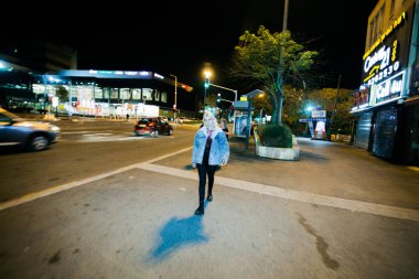 Genç hippi kadın gece yarısı sokakta yürüyor.