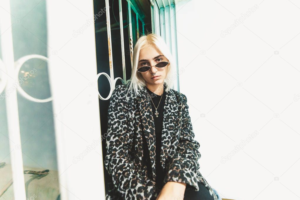 Blonde hipster young woman posing on window sill