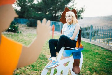 Portrait of young blonde woman sitting on playground clipart