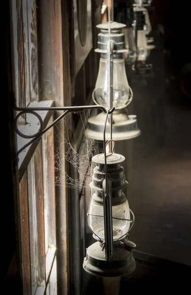 A row of ancient oil lamps covered in dust and cobwebs