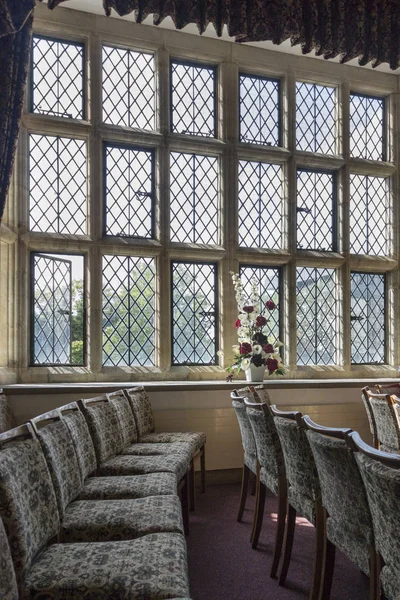 An ancient room interior with leaded windows and rows of chairs