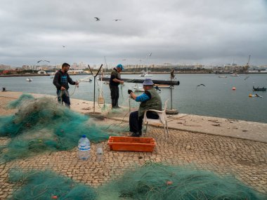 Limandaki itfaiyeciler ağdaki yengeçleri ve balıkları, Algarve, Portekiz 'deki Ferragudo' yu temizliyor.