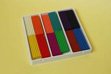 Sarı arka plan üzerinde çok renkli plastik içeren bir kutu.