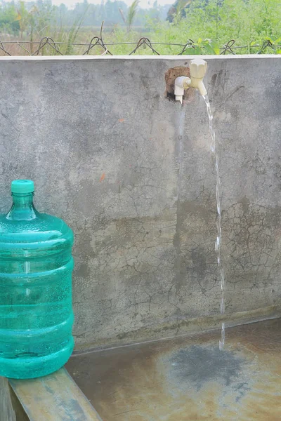 クレーンやペットボトルから流れる水を持つコンクリート壁 — ストック写真