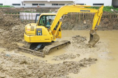 Komatsu Pc 71 ekskavatör suda dururken zemin kazıyor. Hindistan'da sel veya inşaat, Mayapur, Mart 5, 2019.