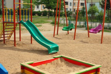 Çocuk oyun alanı: salıncaklar, döner kavşaklar, kaydırak ve kum havuzu. Belarus'ta bir apartmanın avluda oynamak için çocuklar için bir yer.