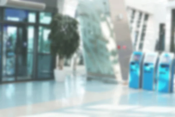 Blurred photo of the interior of a bank or hall in an office space, at the airport with self-service terminals or ATMs. Defocused substrate.