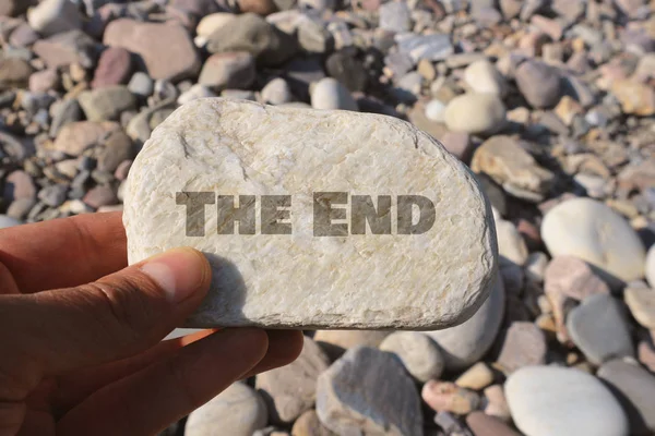 hand holding rock with the end lettering in bright sunlight