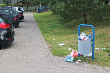 Taşan çöp tenekesi ve çimenlikteki çöp. Beyaz Rusya, Minsk, 14 Temmuz 2019.
