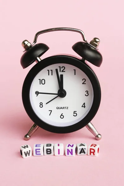 pembe arka plan üzerinde webinar küp harfleri ile siyah çalar saat 
