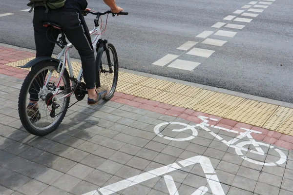 Yaya geçidinde bisikletçi. Bisikletli adam bisiklet için işaretlerle yolun karşısına geçiyor. Beyaz Rusya, Minsk, 6 Temmuz 2019.