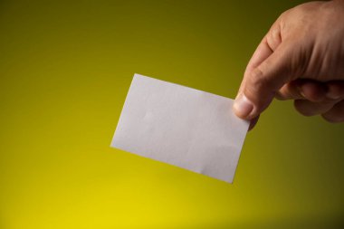 Sarı arka planda beyaz kağıtlı erkek eli.