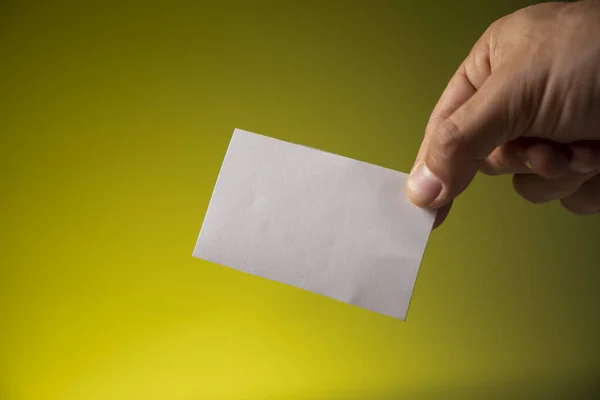 Sarı arka planda beyaz kağıtlı erkek eli.