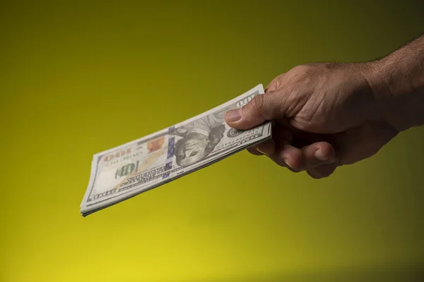 Bir el dolar tutar sarı bir yüzey, yakın - para konsepti