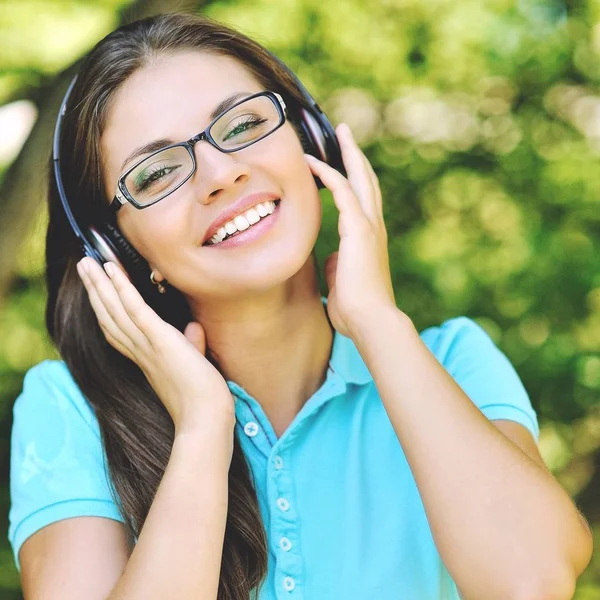 Hermosa mujer joven con auriculares al aire libre. Disfrutando de la música —  Fotos de Stock