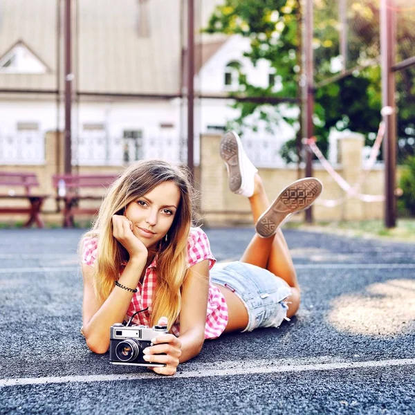 Mooi lachende meisje liggend op een grond met oude retro camera — Stockfoto