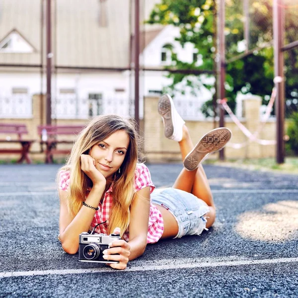 Menina sorridente bonita deitada em um chão com câmera retro velha — Fotografia de Stock