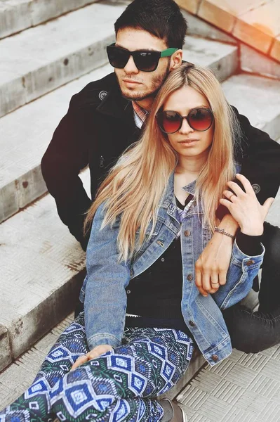 Fashionable young couple sitting on stairs and hugging each other — Stock Photo, Image