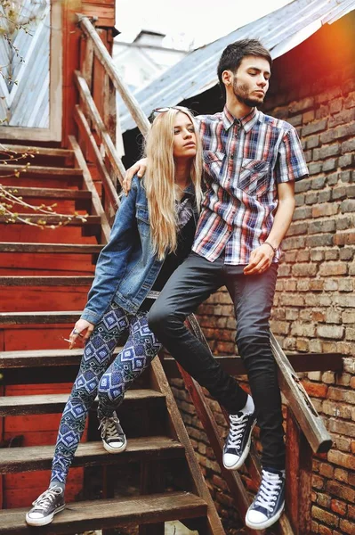 Fashionable young couple standing on stairs and hugging each other — Stock Photo, Image