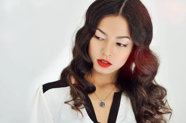 Mooi meisje met rode lippen en krullend zwart haar op witte achtergrond — Stockfoto