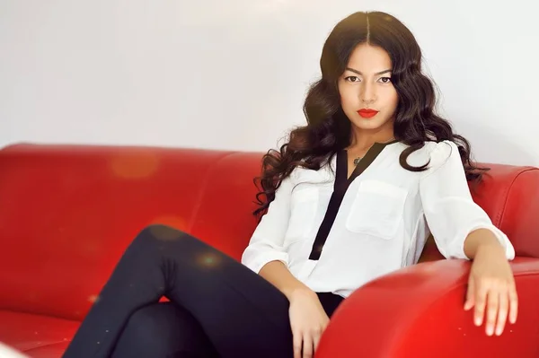 Mode meisje, zittend op een rode sofa thuis — Stockfoto