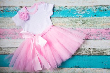 Bebek set - pembe tül etek, kalplerin beyaz gömlek ve bir güzel pembe kafa bandı pastel ahşap arka plan üzerinde. Üstten görünüm, düz yatıyordu.